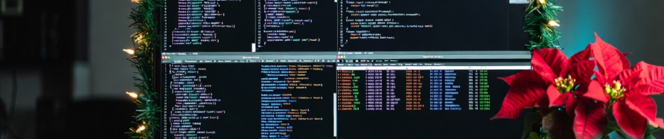 Weekly Dev Chat IRL: Advent of Code/Cyber header. Monitor with code on it surronded by Christmas lights.